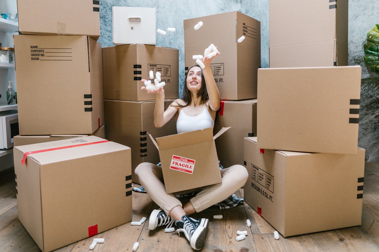 Young woman surrounded by cardboard boxes, happily moving into her new apartment.